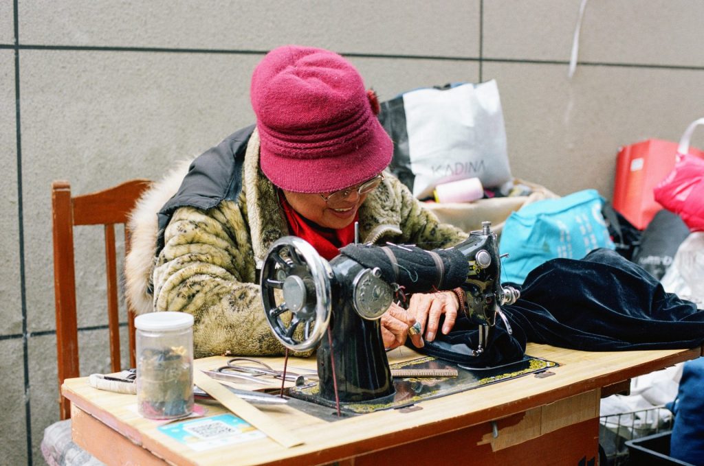 Woman sews with an antique sewing machine.
